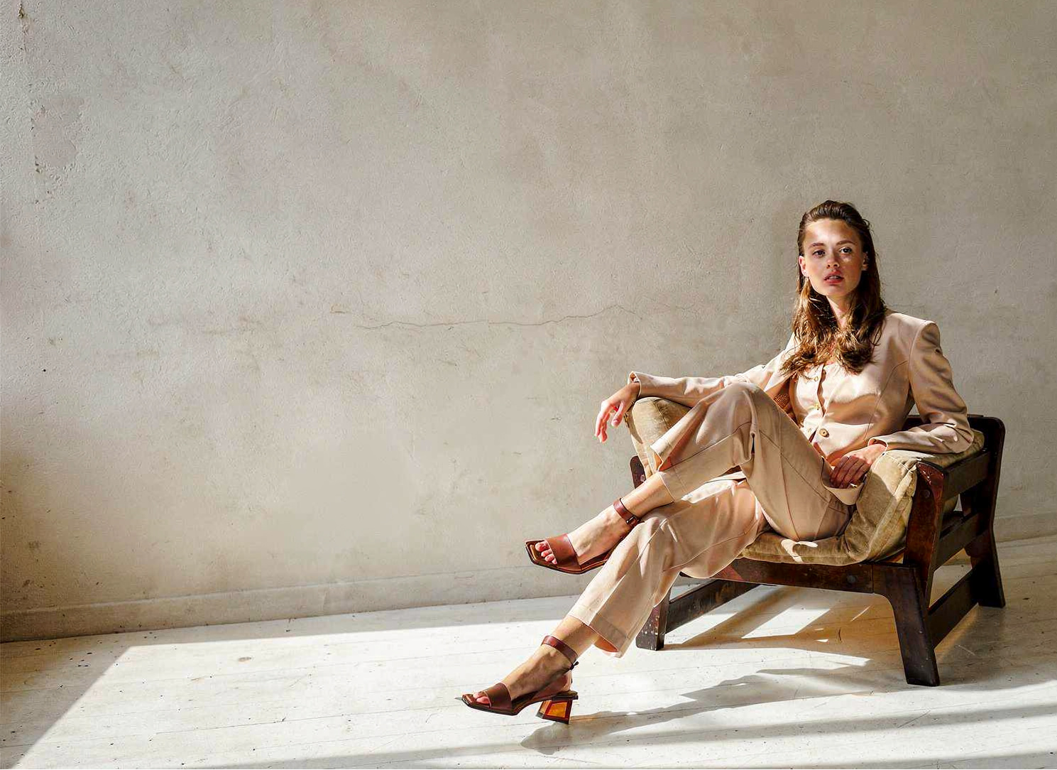 Woman sitting on a chair in a minimalistic room with soft lighting